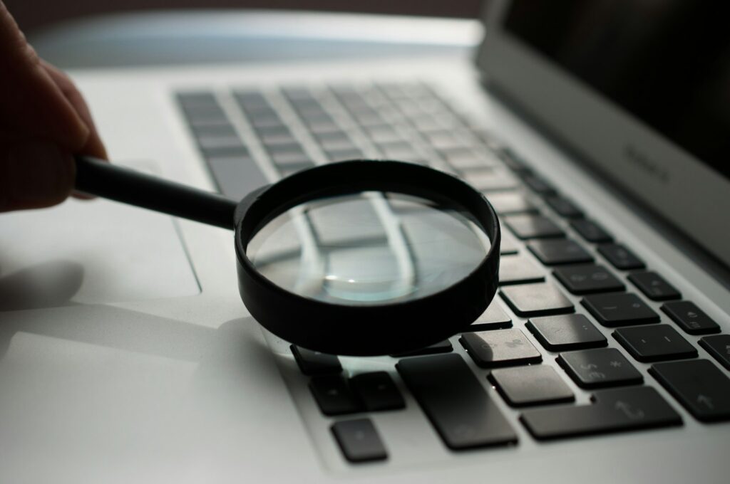 Lupa sobre um portátil, simbolizando a técnica Chain-of-Thought e a auto-verificação de respostas de IA