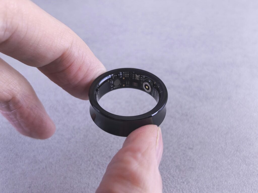Dedos a segurar um anel inteligente preto, semelhante ao Oura Ring 4